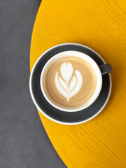 Latte art coffee sitting on yellow table in cafe
