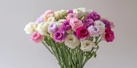 Eustoma bouquet featuring white, pink, and purple flowers arranged at center against a soft gray-white backdrop for a delicate aesthetic.