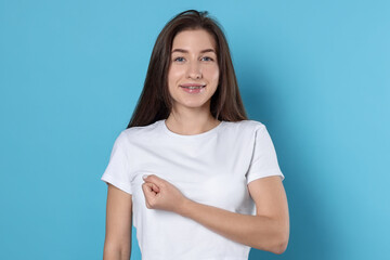 Woman making promise on light blue background. Oath gesture