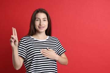 Woman showing oath gesture on red background, space for text. Making promise