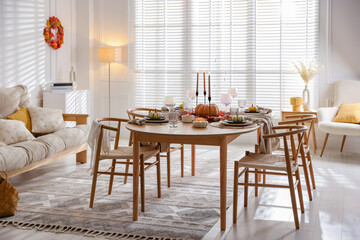 Stylish table setting with beautiful dishware and autumn decor in dining room