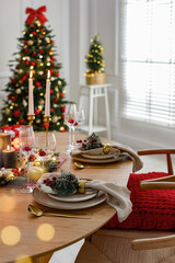 Christmas celebration. Festive table setting with dishware, glasses and decor in room