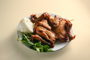 whole Ayam Penyet with sambal, basil and cucumber served in brown paper, showcasing Indonesian cuisine