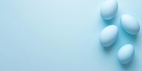 Minimalist flat lay of four soft blue eggs arranged on a pastel blue backdrop with ample copyspace for text on the right side