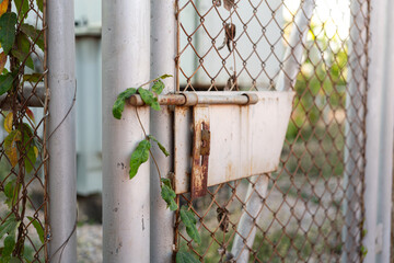 Closed locking wire fence door with rustic handle at the abandoned place. Building object close-up photo.