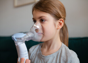 Cute little baby in the mask of an inhaler. Procedure of inhalation at home. Baby taking...