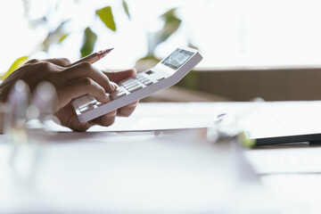 A businessman analyzing financial charts and data on a digital tablet in a modern office. Surrounded by reports, graphs, and a laptop, he plans strategies for growth, investment, and corporate success