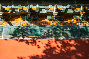 A red wall in the traditional style of ancient Chinese under the shadow of a tree