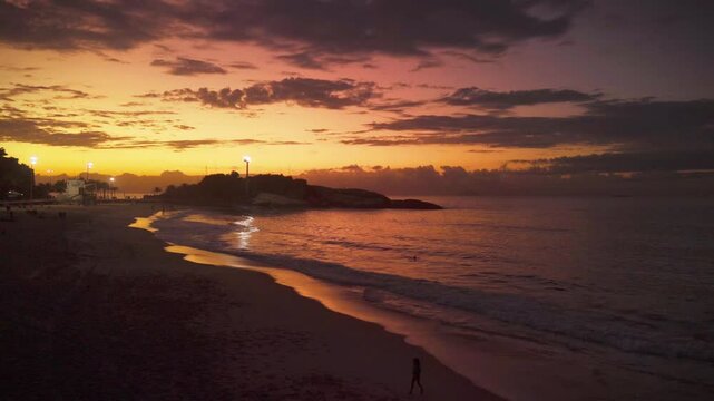 sunrise in Arpoador Beach in Rio de Janeiro with the sea reflecting the sun with orange and yellow colors