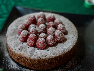 Chocolate cake topped with raspberries and dusted with powdered sugar