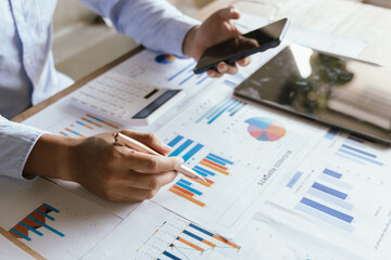 A businessman is analyzing financial data on a laptop surrounded by charts, documents and reports. He focuses on investment planning, budgeting and tax strategies for economic success.