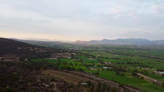 Vista aerea del campo en un pueblo al atardecer con monta&ntilde;as al fondo 