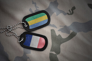 vintage army blank, dog tag with flag of gabon and france on the khaki texture background. military...