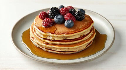 A stack of fluffy pancakes topped with fresh berries and drizzled with syrup, served on a simple plate.