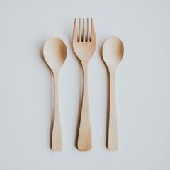 Polished wooden dining spoon and fork set arranged on a flat white surface for elegant dining presentation