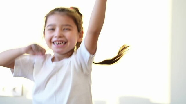 view of active awake little girl 5 years old having fun singing favorite song enjoying hobby in morning spending leisure time jumping in room. High quality 4k footage
