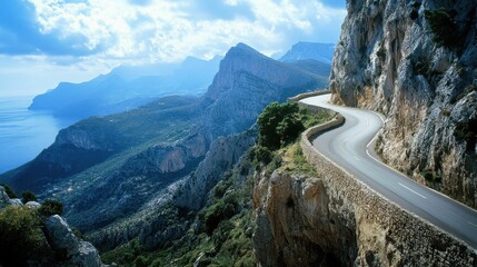 Winding mountain road offers breathtaking views of cliffs and the coastline during a sunny day