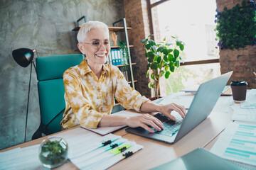Photo of lovely pensioner lady typing netbook dressed yellow print shirt formalwear comfortable...