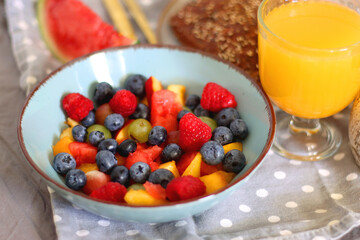 Tray with various healthy breakfast food, open book and reading glasses on the bed. Breakfast in bed concept. Selective focus.