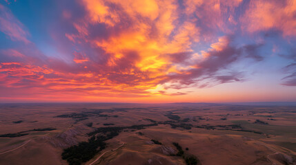 A vibrant sunset seen from a hot air balloon with the vast landscape below glowing in warm golden hues.
