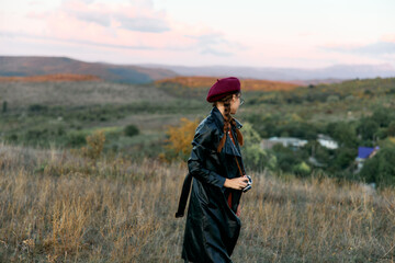 Mysterious woman in red hat and black coat standing alone in the vast field on a foggy morning