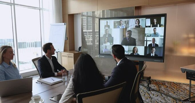 Different businesspeople engaged in formal discussion using videocall application, look at screen displayed multiethnic professionals, negotiate, solve joint business remotely. Digital communication