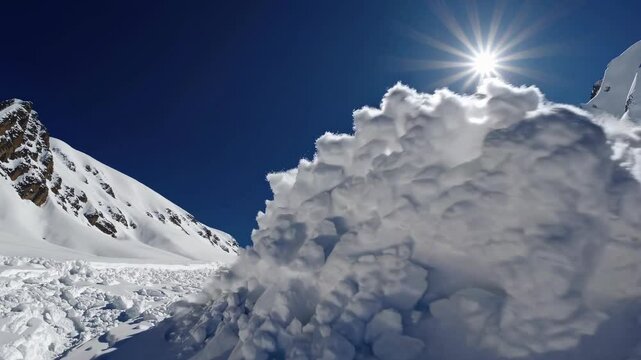 Massive white snow avalanche cascading down steep mountainside, generating billowing powder cloud against pristine blue sky and bright sunlight, revealing nature's raw destructive power