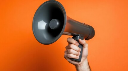 hand gripping a megaphone against an orange backdrop, symbolizing marketing and sales communication, conveying a message of outreach and engagement