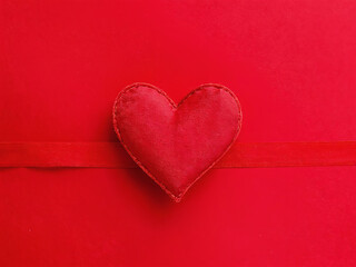 Heart-shaped decoration on a red background with matching ribbon creates a romantic atmosphere for special occasions. Valentine&rsquo;s Day, date, engagement, love, wedding, background