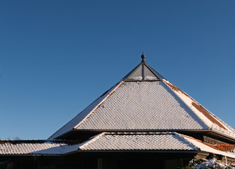 Schneebedecktes Dach der Friedhofskapelle vor blauen Himmel