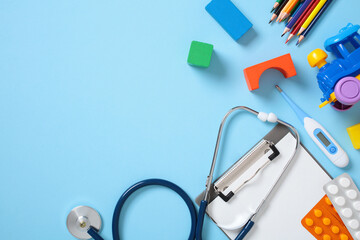Medical tools and colorful children toys on a blue background, including a stethoscope, clipboard, thermometer, pills, colored pencils, and toy blocks