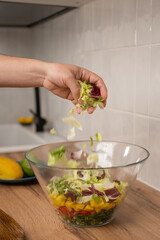 Close-up of a man's hand making salad in the kitchen