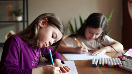 children girls draw with pencils and markers at the table at home. kids art, leisure and hobbies