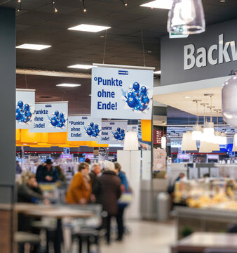 Aachern, Germany - Jan 3, 2025: Interior of an Edeka store featuring signs advertising the new PAYBACK loyalty card system, replacing DeutschlandCard, with shoppers and bakery section visible.