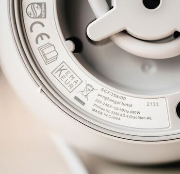 Strasbourg, France - Oct 25, 2023: A close-up view of the underside of a Philips SCF358 00 bottle warmer, displaying technical specifications, certifications, and manufacturing details.