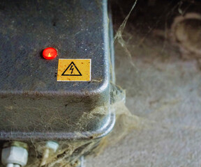 Close-Up of Electrical Warning Sign on Metal Surface With Red Light Indicator