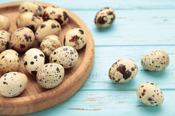 Fototapeta premium Quail eggs in wooden plate on blue wooden background