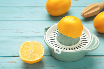 Squeezer and lemons on blue wooden background