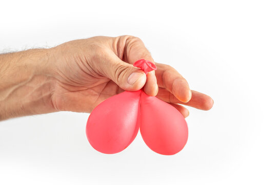 A man's hand holding two balloons symbolizing testicles. The concept of male health, fertility