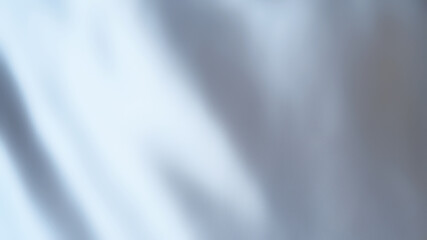 Silver satin fabric background. Blurred cloth texture backdrop of white silver with luxury, grey, and simplicity wave concepts. Close-up rippled silver fabric texture for wallpaper and background.