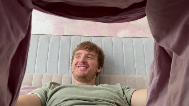 man looking under blanket and happy, feeling excited, concept men's health, bed