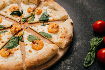 Close-up of seafood pizza slice with shrimp, spinach, and melted cheese on a wooden platter.
