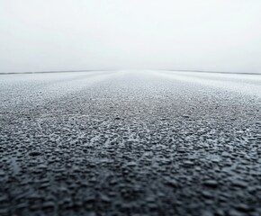 Wet road stretches into fog, creating a serene yet mysterious atmosphere in early morning light