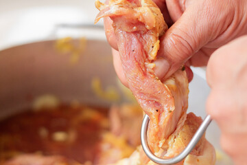 Process of securing a meat cut with a hook for smoking. Utensils for hanging meat on grill.