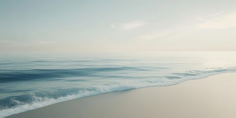 Soft waves gently touch the sandy shore as the horizon glows with the early light of dawn, creating a serene and peaceful atmosphere by the ocean