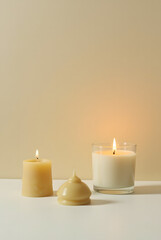 Handcrafted olive wax candles in various shapes, burning against a duotone pastel background. Minimalist design, creating a cozy and modern atmosphere.