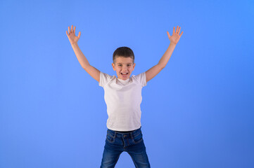 Portrait of adorable cute boy with arms raised screaming and standing isolated over blue background