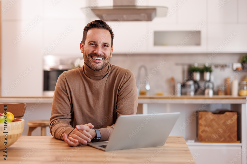 Wall mural positive male entrepreneur with computer on dining table smiling at camera while working from home