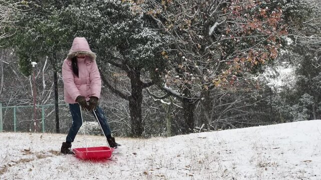冬の公園で楽しく雪遊びしている小学生の女の子の様子