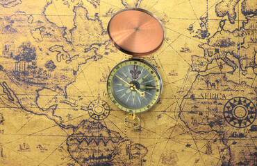 Classic round compass on background of old vintage map of world